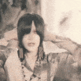 a woman with long black hair is covering her ears with her hands while wearing earrings .