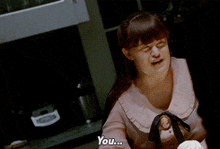 a woman sitting at a table with a plate of cupcakes and the word bitch on the table