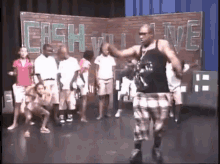 a group of people are dancing on a stage in front of a wall that says cash will live
