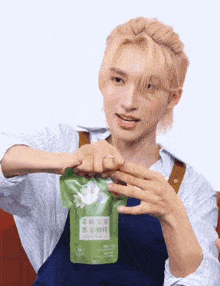 a man with blonde hair is opening a green bag