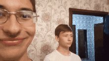 a man wearing glasses and a white shirt is smiling