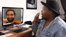 a woman wearing a hat looks at a computer screen with a man on it