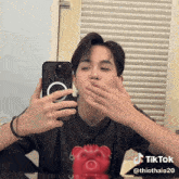 a man covering his mouth with his hand while taking a picture of himself in a tiktok video