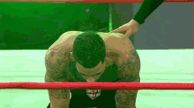 a man in a black shirt with a shield on it is kneeling in a ring