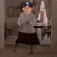 a man wearing a tampa bays hat is dancing in a living room