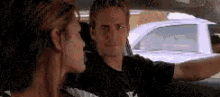 a man and a woman are sitting in the back seat of a car talking to each other .