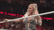 a woman in a zebra print dress is standing in a wrestling ring with a w logo in the background