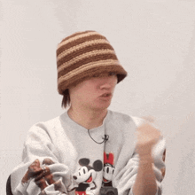 a person wearing a mickey mouse sweatshirt and a striped hat