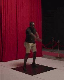 a man is dancing on a dance floor in front of red curtains .