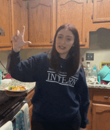 a woman wearing a blue sweater that says intern on it