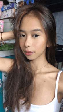 a woman in a white tank top takes a selfie in front of a sign that says 2h