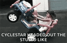 a little girl is sitting in a jeep that has been turned on its side .