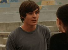 a man in a gray shirt talks to a woman