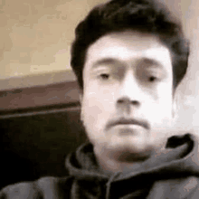 a man in a hoodie is taking a selfie with his phone .