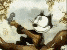 a cartoon cat is sitting on a tree branch holding a bird .
