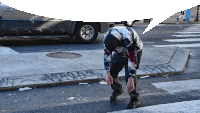 a man in a tie dye shirt is tying his shoelaces on a sidewalk