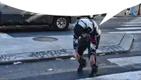 a man in a tie dye shirt is tying his shoelaces on a sidewalk