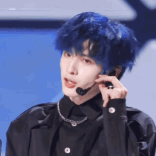 a man with blue hair is wearing a black shirt and a chain necklace