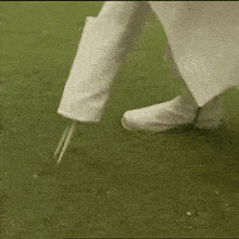 a person is holding a golf club on a tee on a green .