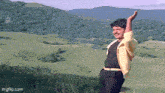 a man is standing in a field with his arms outstretched .