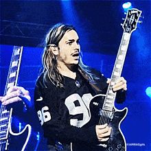 a man with long hair is playing a guitar and wearing a jersey with the number 96 on it