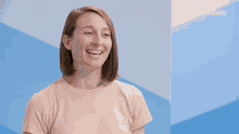 a woman laughs in front of a blue wall that says elite daily on it