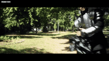 a man in armor is walking through a park with a webvideo watermark on the bottom right