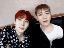 two young men are sitting next to each other and one of them is wearing a heart print shirt
