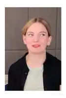 a woman wearing a grey shirt and a black jacket is looking up