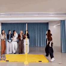 a group of people are standing around a yellow pole in a room with a sign that says ' korean ' on it
