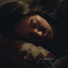 a woman is sleeping on a striped pillow