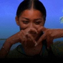a woman making a heart shape with her hands in front of her face