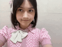 the girl is wearing a pink dress with white polka dots and a white bow .