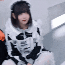 a girl in a maid costume is sitting on a couch .