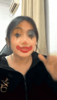a woman is wearing a black jacket and making a clown face with red lipstick .