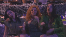 three women are sitting in front of a table with zebra print .