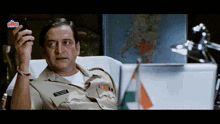 a man in a police uniform is holding a cell phone in front of a map that says ultra