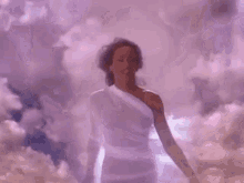a woman in a purple dress is standing in the clouds .