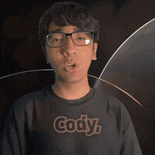 a man wearing glasses and a black shirt that says gody on it