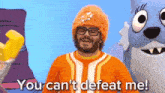 a man wearing an orange hat and glasses says you can 't defeat me .