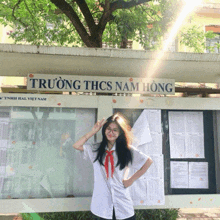 a girl stands in front of a bulletin board that says truong thcs nam hong