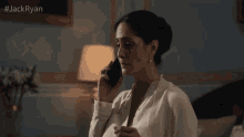 a woman in a white shirt is sitting in front of a lamp with the hashtag jackryan on the bottom