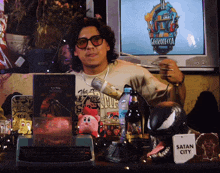 a man sitting in front of a tv with a sign that says satan city on it
