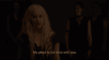 a woman is standing in a dark room with a group of people and says `` my place is not here with you . ''