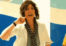 a man wearing a scarf and a white shirt is making a face