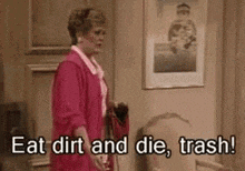 a woman is standing in a living room holding a broom and saying `` eat dirt and die , trash ! '' .