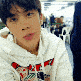 a young man wearing a white hoodie with a red and green graphic on the front