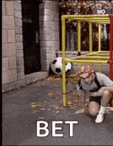 a man is crawling under a ladder with a soccer ball .