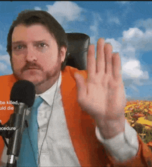 a man in a suit and tie is sitting in front of a microphone with the words " be killed uld die " on the bottom