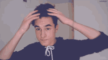 a young man wearing a black hoodie with white laces is holding his hair